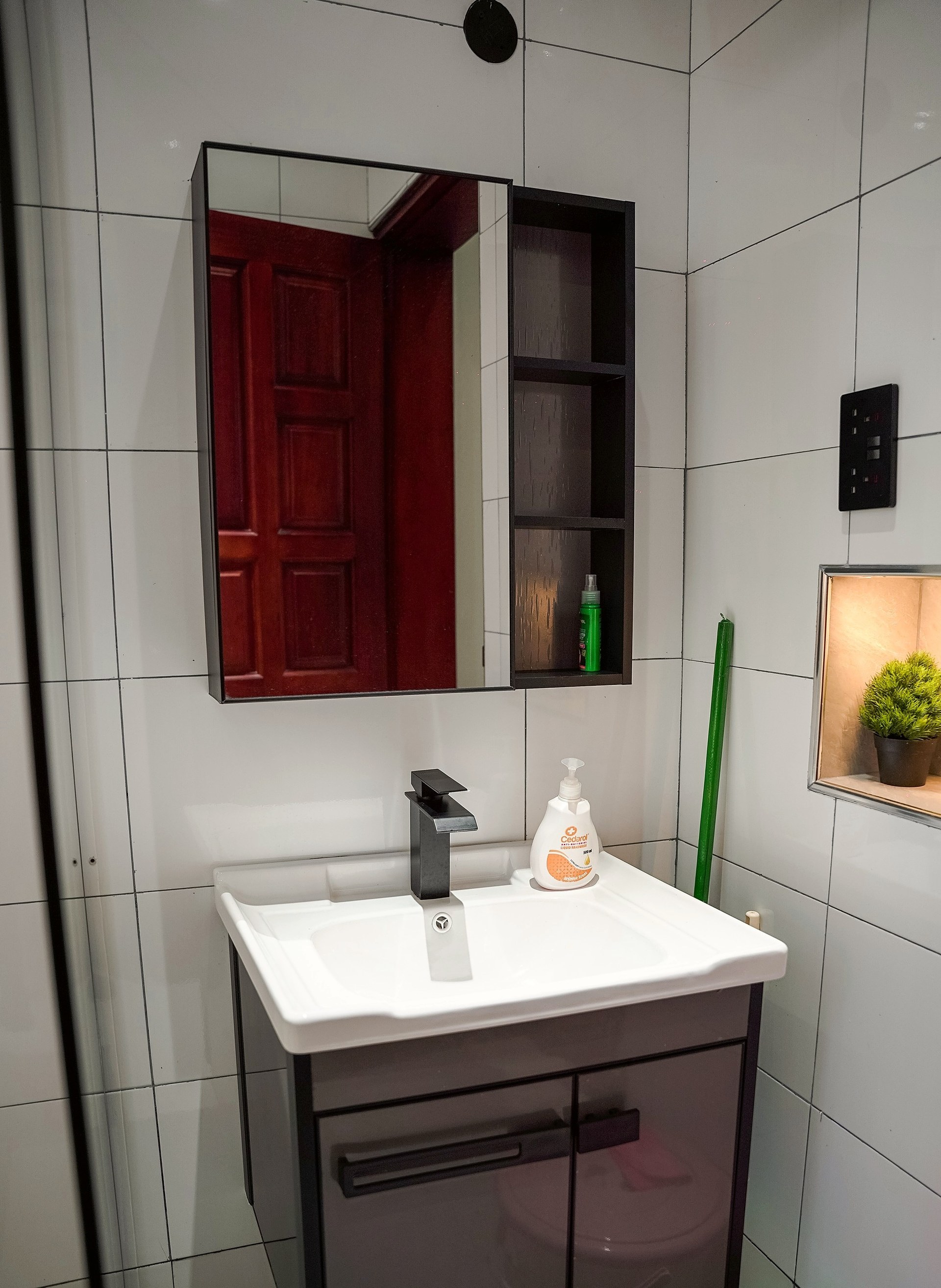 Bathroom vanity with a black tap and a mirrored cabinet